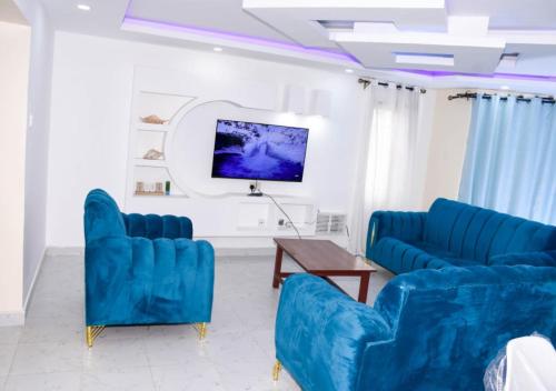 a living room with two blue chairs and a tv at Madaraka - Nairobi West in Nairobi