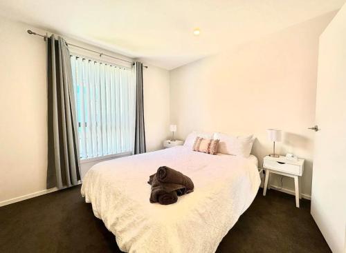 een slaapkamer met een groot bed met een rugzak erop bij Immaculate - 2 Bedroom Townhouse close to the train station in Auckland
