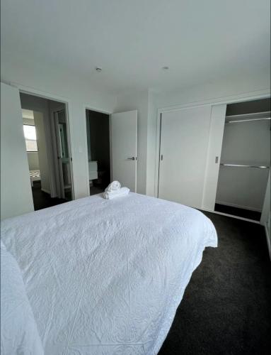 a bedroom with a white bed with a white blanket at Immaculate - 2 Bedroom Townhouse close to Fruitvale train station in Auckland