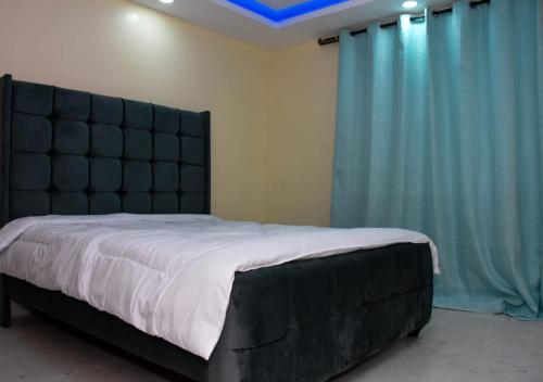 a bedroom with a large bed with a black headboard at Madaraka - Nairobi West in Nairobi