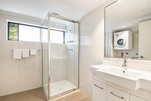 a bathroom with a shower and a sink and a mirror at Cape Apartments in Byron Bay