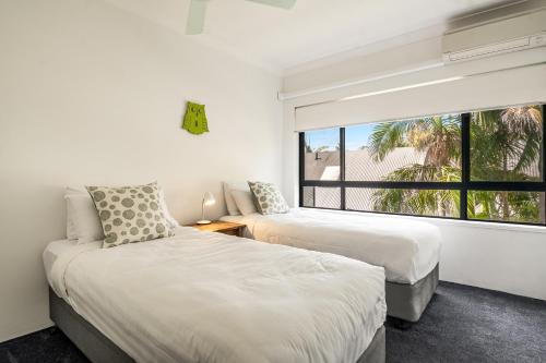 two beds in a room with a window at Cape Apartments in Byron Bay
