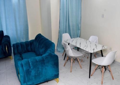 a living room with a blue couch and a table and chairs at Madaraka - Nairobi West in Nairobi