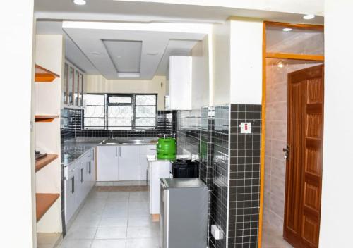 a large kitchen with white cabinets and black tiles at Madaraka - Nairobi West in Nairobi