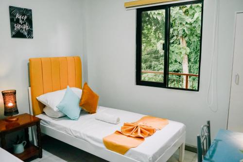 a bedroom with a bed with an orange headboard and a window at Near Airport Transient Inn - 2 Bedroom Suite in Puerto Princesa City