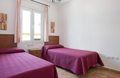 een kamer met 2 bedden met paarse lakens en een raam bij Apartamento Pérez Zara 6 in Conil de la Frontera