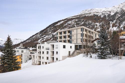a building in the snow in front of a mountain at Hotel Maistra 160 in Pontresina