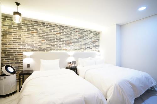 two beds in a bedroom with a brick wall at Dongdaemun Saturn Hotel in Seoul