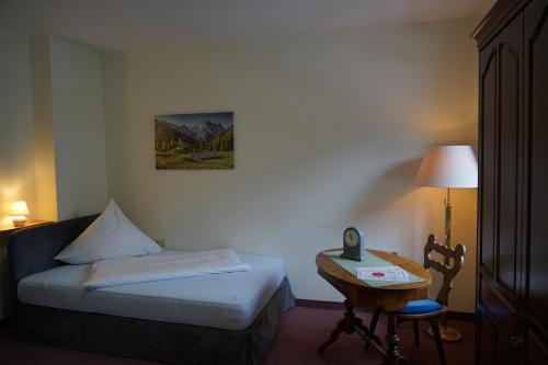 Schlafzimmer mit einem Bett und einem Tisch mit einem Telefon in der Unterkunft Hotel Garni Schlossblick in Hohenschwangau