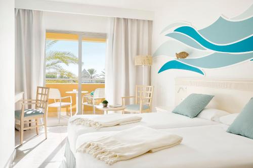 モロ・デル・ハブレにあるIberostar Playa Gaviotas Park All Inclusiveのベッド2台とテーブルが備わるホテルルームです。