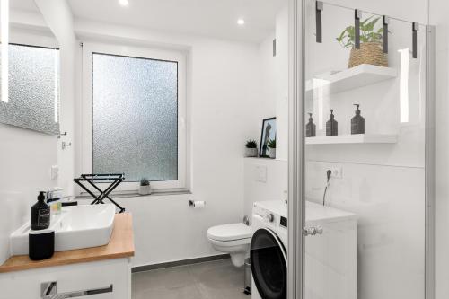 ein weißes Bad mit einem WC und einem Waschbecken in der Unterkunft SoWi Design - Gartenblick & Parkplatz, Küche in Kassel