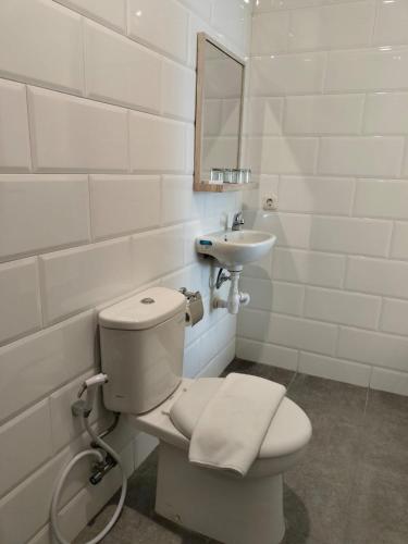 a white bathroom with a toilet and a sink at Key Inn Hotel Bogor in Kamparganya