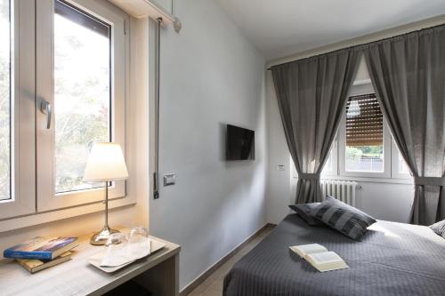 a bedroom with a bed and a desk and windows at B&B Civico 1 in Pavia