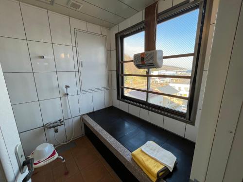 La salle de bains est pourvue d'une grande fenêtre et d'une baignoire bleue. dans l'établissement LiVEMAX RESORT Shiretoko Sea Front, à Rausu