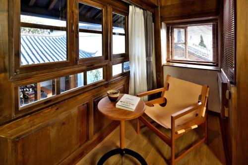 a small table and a chair in a room with windows at 丽江南渡观景客栈 Nundo Recreation Terrace in Lijiang