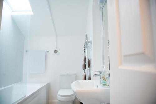 a white bathroom with a sink and a toilet at Trinity, Central Cambridge Flat in Cambridge