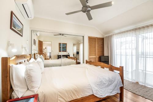 a bedroom with a large white bed and a mirror at Franche Brise a la Mer in Byron Bay