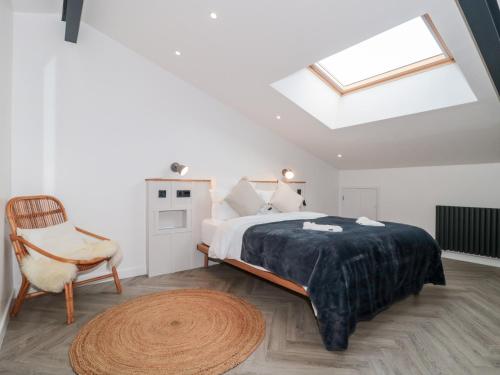 a bedroom with a bed and a chair and a skylight at Basswood Barn in Wincanton