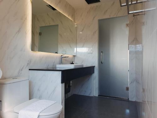 W łazience znajduje się toaleta, umywalka i lustro. w obiekcie The Sila Suites - Intrawarorot w mieście Chiang Mai