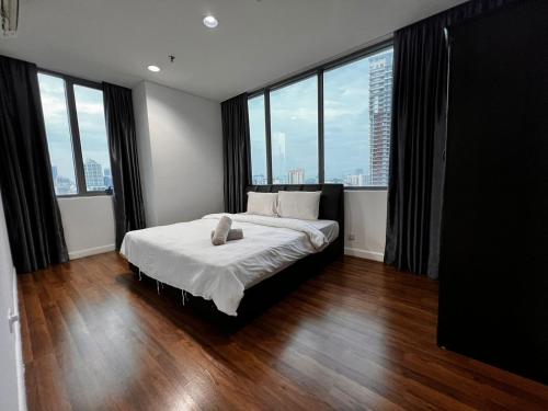 sypialnia z dużym łóżkiem i dużymi oknami w obiekcie Summer Suites KLCC By Homestay w Kuala Lumpur