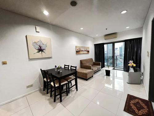 een woonkamer met een tafel en een bank bij Summer Suites KLCC By Homestay in Kuala Lumpur