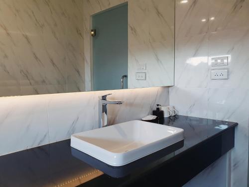 bagno con lavandino bianco e specchio di The Sila Suites - Intrawarorot a Chiang Mai
