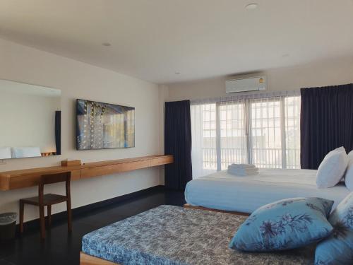 Un dormitorio con una cama, un escritorio y una ventana. en The Sila Suites - Intrawarorot, en Chiang Mai