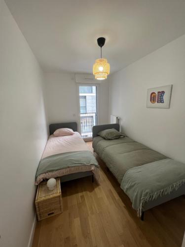 deux lits dans une petite pièce avec une fenêtre dans l'établissement appartement 4 pièces spacieux grande terrasse, à Clichy
