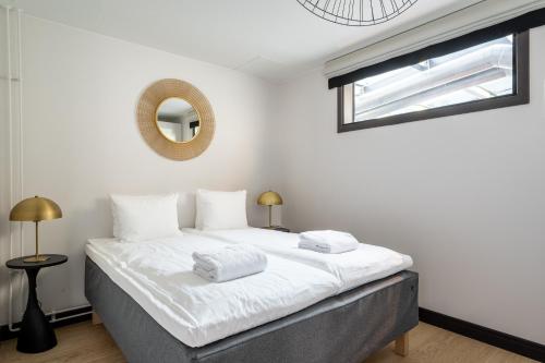 a bedroom with a bed with white sheets and a mirror at Bob W Koti Katajanokka in Helsinki