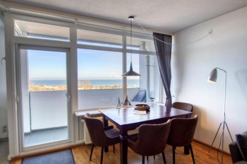 ein Esszimmer mit einem Tisch und einem großen Fenster in der Unterkunft Ferienpark - Haus A, App 0A0703 in Heiligenhafen