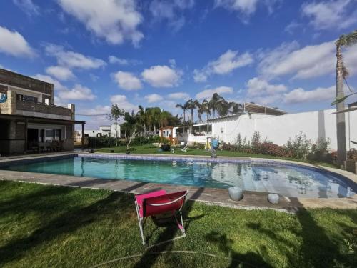 - une piscine avec une chaise rose dans l'herbe dans l'établissement Appartement 32 Ensoleillé à 5min de la Plage, à El Jadida
