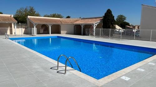 une grande piscine bleue devant une maison dans l'établissement Maison de vacances dans résidence MARINES avec piscine commune, 4 couchages, 250 m de la mer à PORTIRAGNES Plage LRMA4, à Portiragnes
