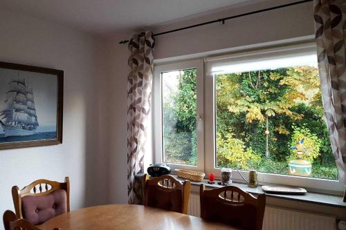 a dining room with a table and a large window at Knurrhahn, Wohnung EG, Dengler in Utersum