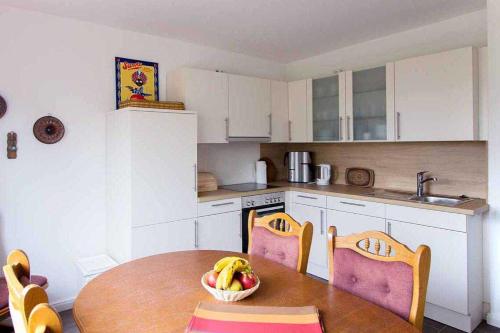 a kitchen with a table with a bowl of fruit on it at Knurrhahn, Wohnung EG, Dengler in Utersum
