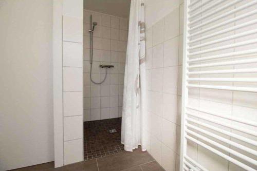 a bathroom with a shower with a shower curtain at Knurrhahn, Wohnung EG, Dengler in Utersum