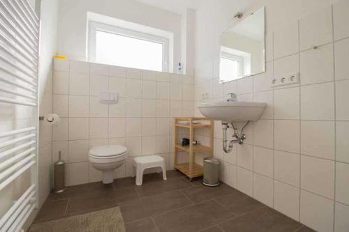 a bathroom with a toilet and a sink at Knurrhahn, Wohnung EG, Dengler in Utersum