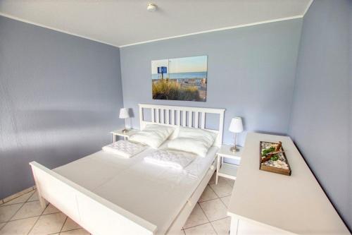 - une chambre avec un lit blanc et une peinture murale dans l'établissement Ferienpark - Haus A, App 0AEG06, à Heiligenhafen