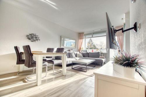 ein Wohnzimmer mit einem Tisch, Stühlen und einem Sofa in der Unterkunft Ferienpark - Haus A, App 0AEG08 in Heiligenhafen