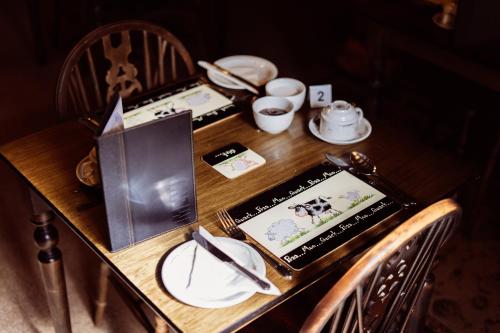 - une table en bois avec des assiettes et un livre dans l'établissement Yallands Farmhouse, à Taunton