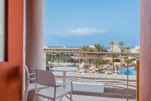 a balcony with a table and chairs and a view of a resort at Iberostar Waves Gaviotas Park in Morro del Jable