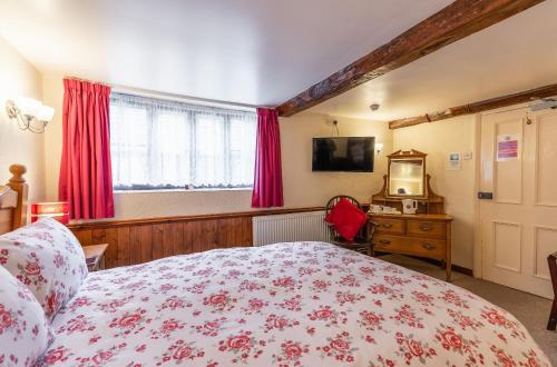 a bedroom with a bed and a television and red curtains at Yallands Farmhouse in Taunton