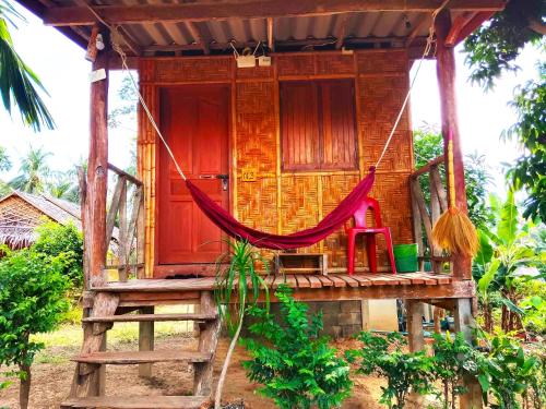 a wooden house with a hammock in front of it at Asama Bungalow in Ko Lanta