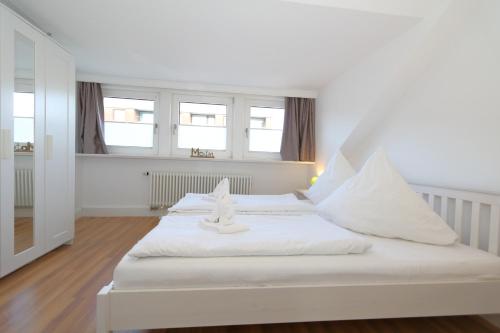 a bedroom with a white bed with white pillows at Haus Sarah App 06 in Westerland