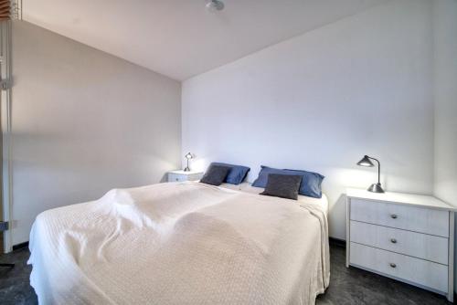 ein weißes Schlafzimmer mit einem weißen Bett und zwei Lampen in der Unterkunft Ferienpark - Haus B, App 0B0408 in Heiligenhafen