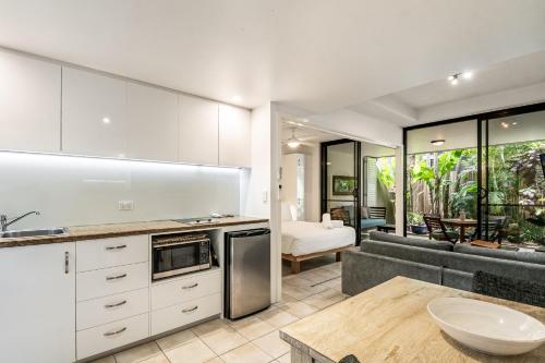 a kitchen with white cabinets and a living room at Julians Apartments in Byron Bay