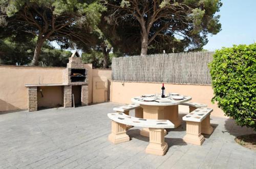 een picknicktafel en bank op een patio met een grill bij Villas Pérez Zara 1, 2 y 3 in Conil de la Frontera
