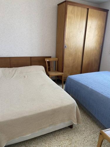 - une chambre avec deux lits, une armoire et une chaise dans l'établissement BOUCANET Appartement P3 vue sur mer - 2 CHAMBRES POUR 6 PERSONNES - LOGGIA, au Grau-du-Roi
