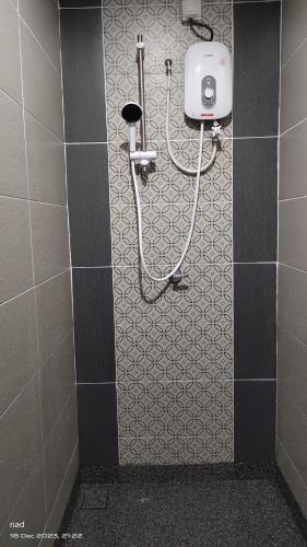 a shower in a bathroom with a tile wall at Tamu d'Bertam Homestay in Kepala Batas