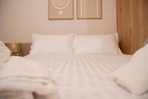 a bed with white sheets and pillows in a room at Ioannina Amazing Deluxe Apartment in Pedini