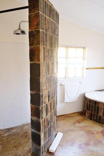 a bathroom with a brick pillar in a room at Crane Cottage in Nottingham Road